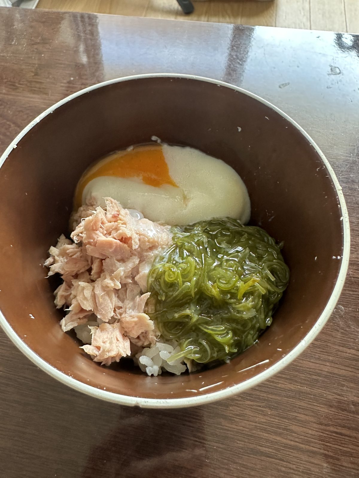昼食（12:03）— 白米ご飯・ツナ水煮・温泉卵・めかぶ（味なし）。めかぶを取り入れた初日の一杯