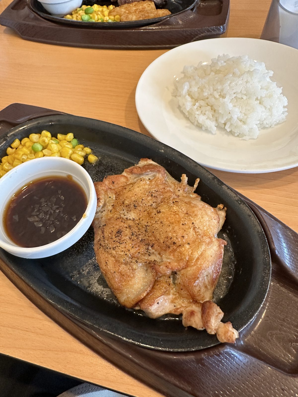 — 昼（11:48）のグリルチキン。鉄板で出てきた鶏もも肉に、白米・コーン・別添えのソース。皮は食べていない。